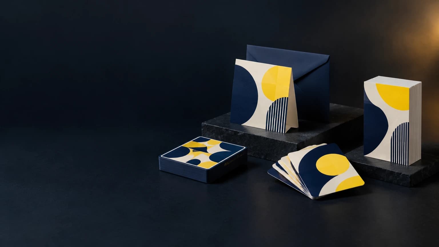 Tarjeta de felicitación doblada ilustrativa con sobre, barajas de tarjetas impresas y pilas de tarjetas de esquina redondeada sobre un fondo oscuro de estudio
